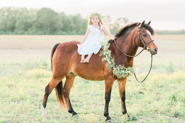 girl with flower crown in dress bareback on pony wearing flower garland