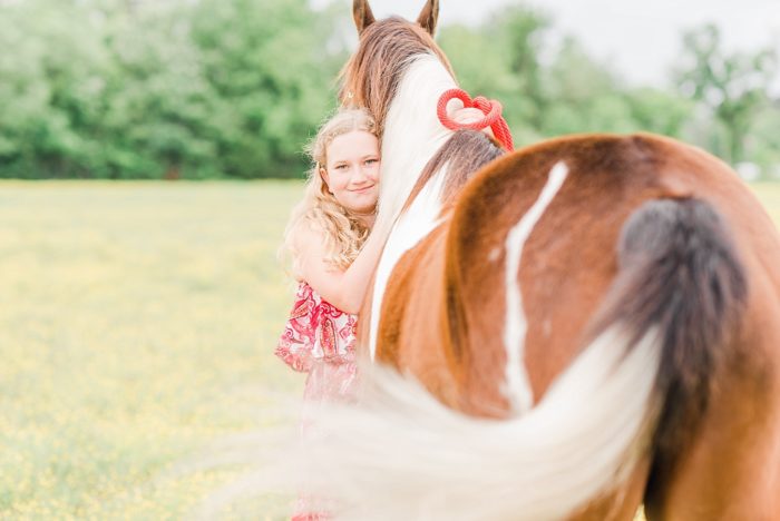 girl hugging her horse in a field