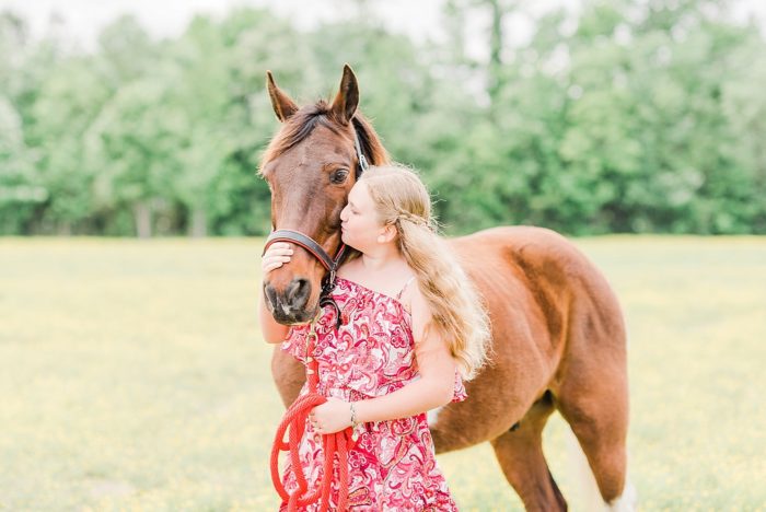 girl kissing her spotted saddle horse in field of buttercups