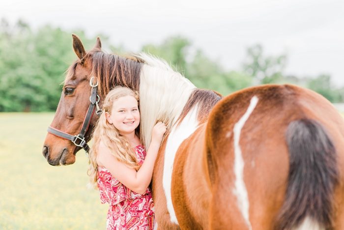 girl hugging horse's chest in field