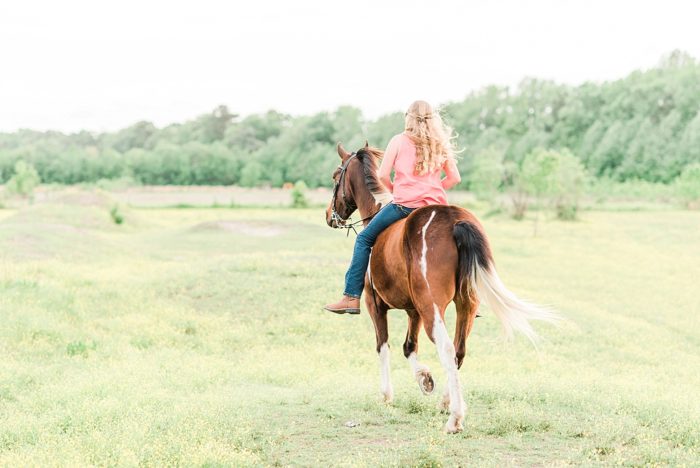 a girl riding a horse away in a field of buttercups