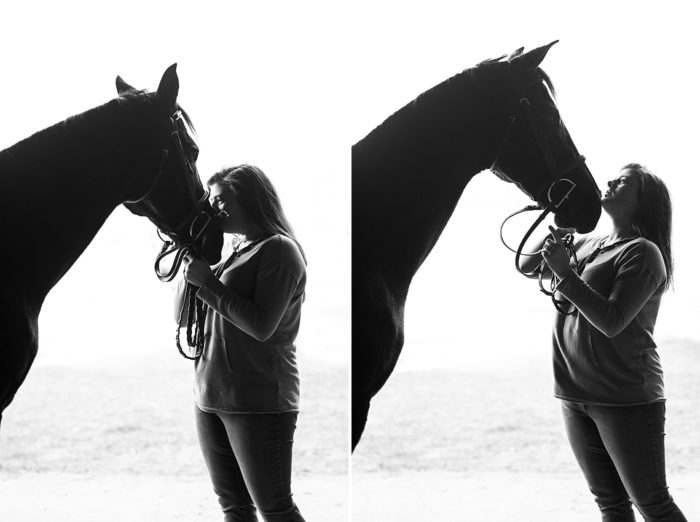 girl kissing horse in barn aisle