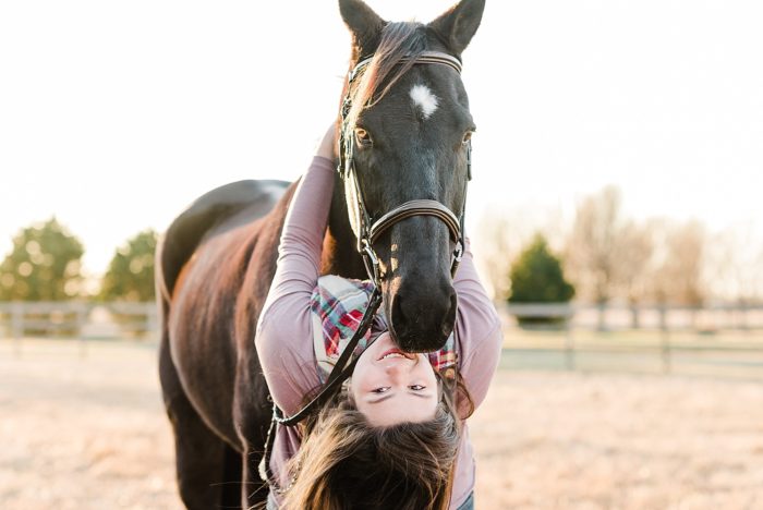 girl hanging from horse's neck